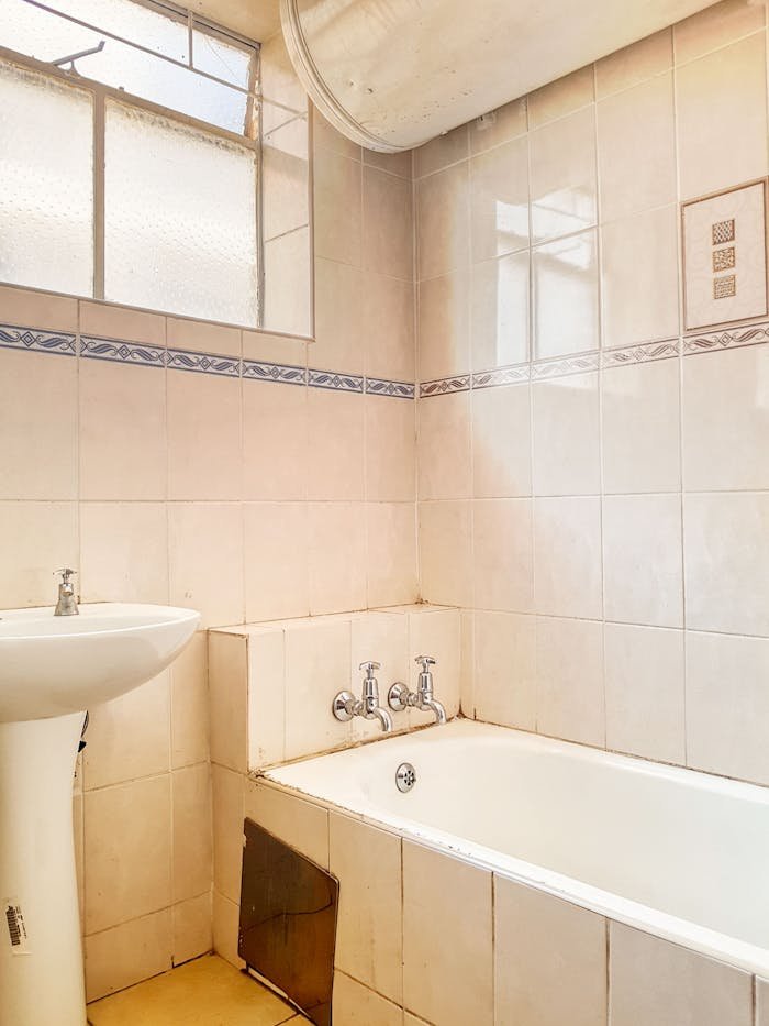 Modern bathroom featuring a bathtub and sink with neutral tile design, ideal for real estate listings.