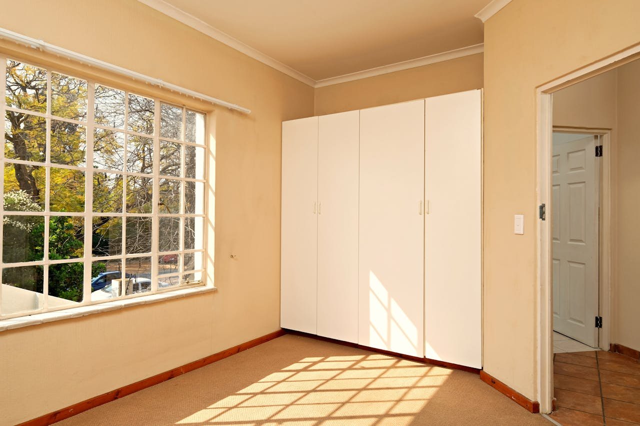 Bright and spacious empty room with a large window and white closet, perfect for modern interiors.